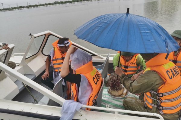 Cảnh sát dùng xuồng giúp dân đưa hài cốt người thân vượt lũ về nhà