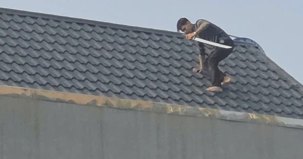 Hai người đàn ông cầm kiếm cố thủ trên mái nhà, công an vây bắt