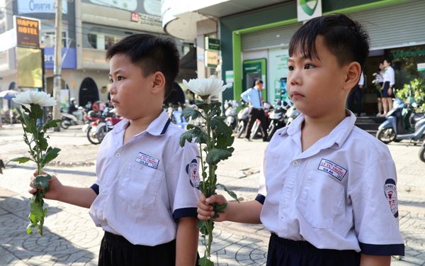 Người dân cầm hoa trắng đợi tiễn đưa các anh
