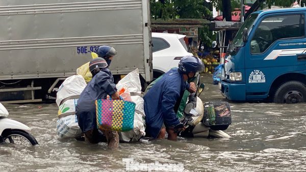 Người và xe ngã nhào trên đường phố ngập sâu ở TPHCM