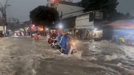Nước chảy như thác cuốn ngã người đi xe máy ở TP HCM sau mưa lớn