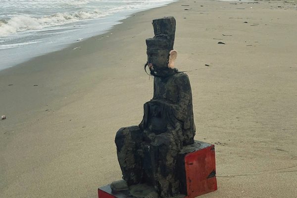 Pho tượng người đàn ông tai to, tay cầm vật giống khăn dạt vào bờ biển